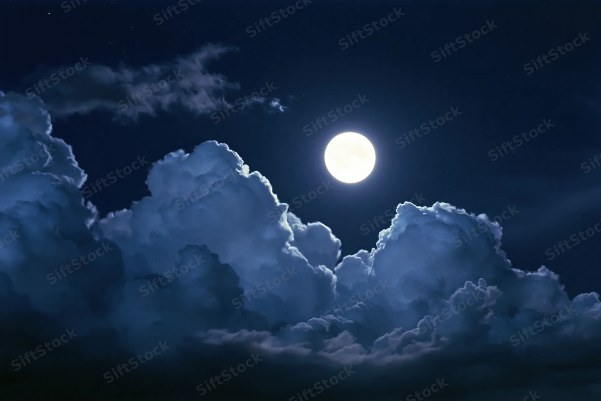 Full moon glowing bright white against deep midnight sky with clouds