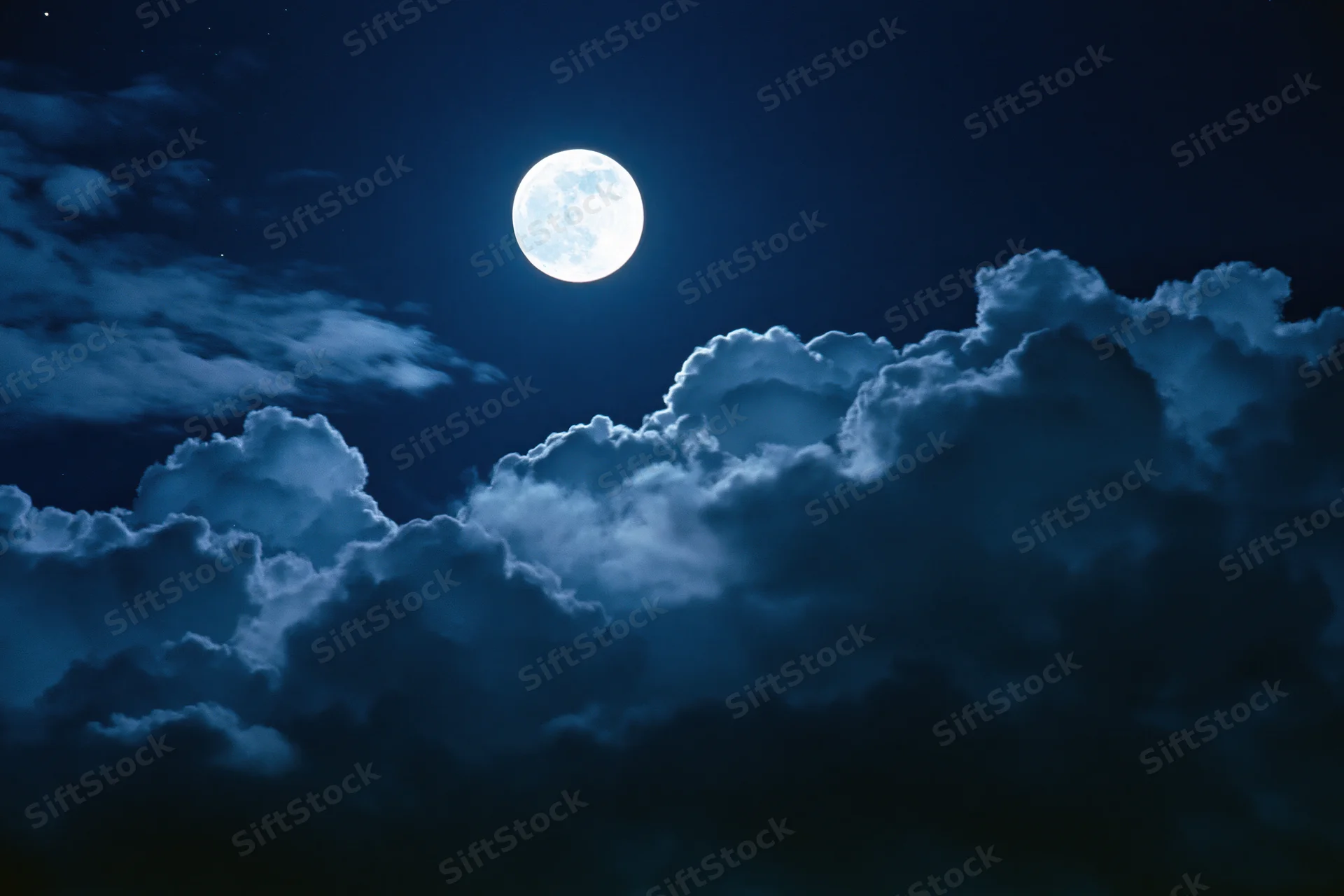 Full moon glowing bright white against deep midnight sky with clouds
