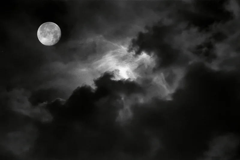 Full moon glowing through dense storm clouds in a dark night sky