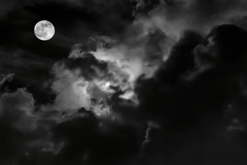 Full moon glowing through dense storm clouds in a dark night sky