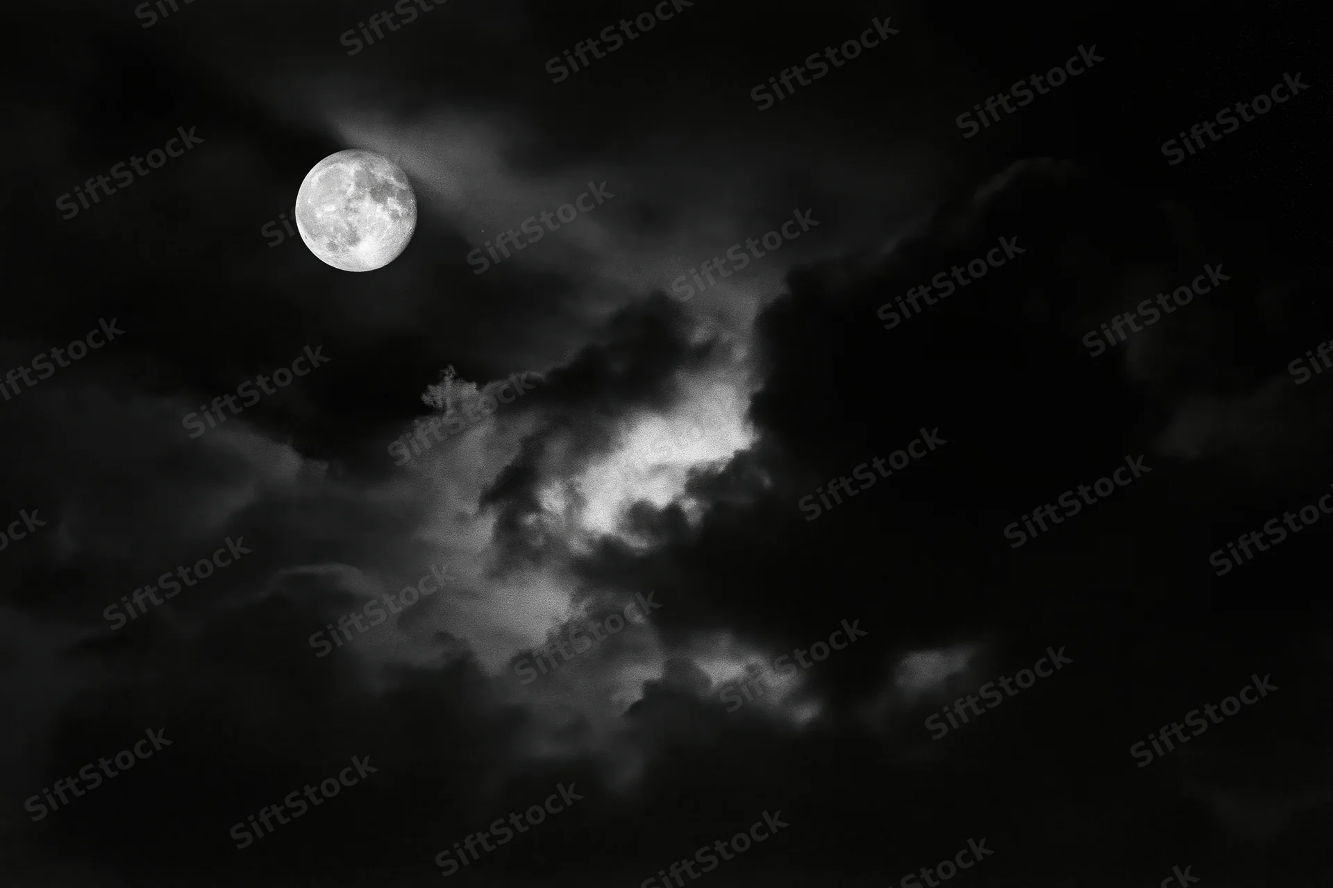 Full moon glowing through dense storm clouds in a dark night sky