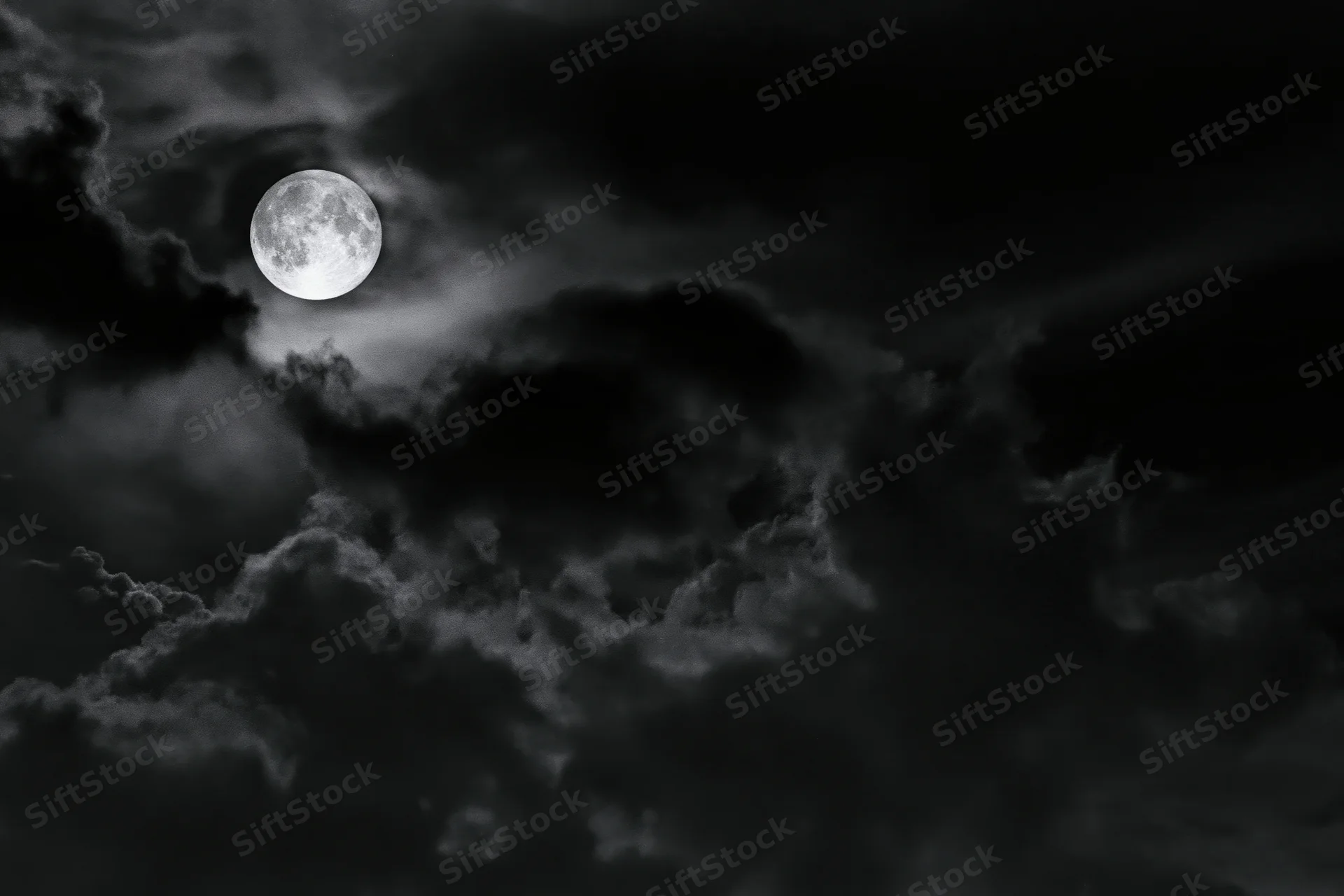 Full moon glowing through dense storm clouds in a dark night sky