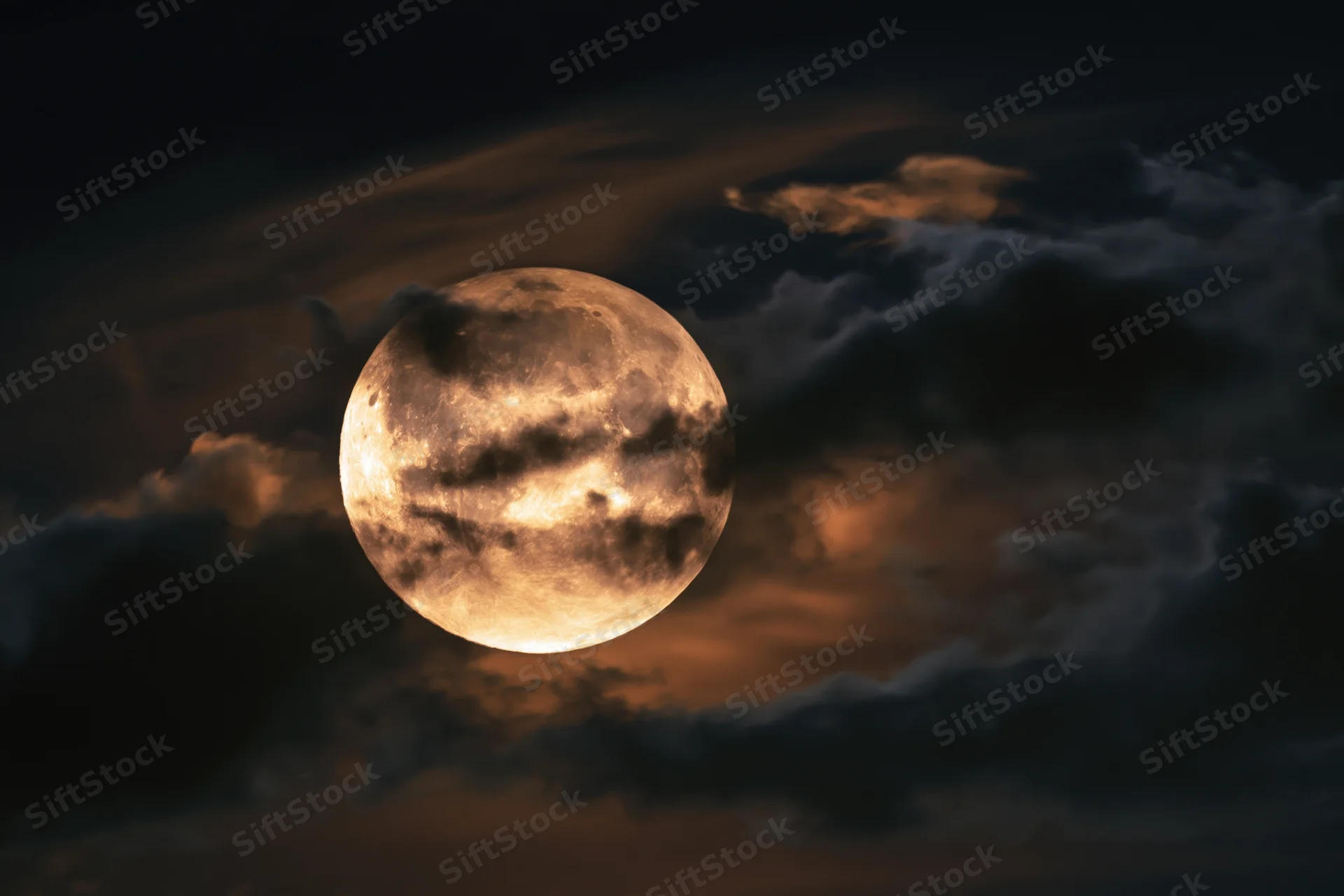 Full moon partially veiled by drifting clouds in the night sky