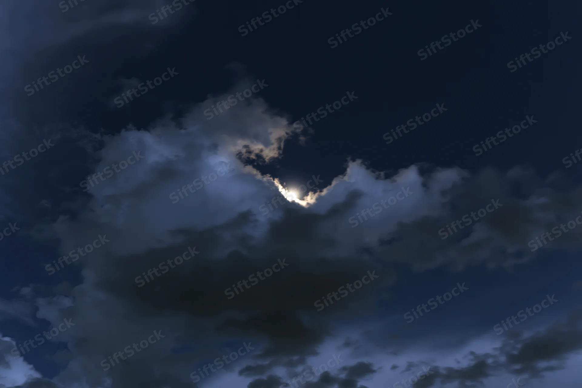 Full moon glowing through broken cumulus clouds at night