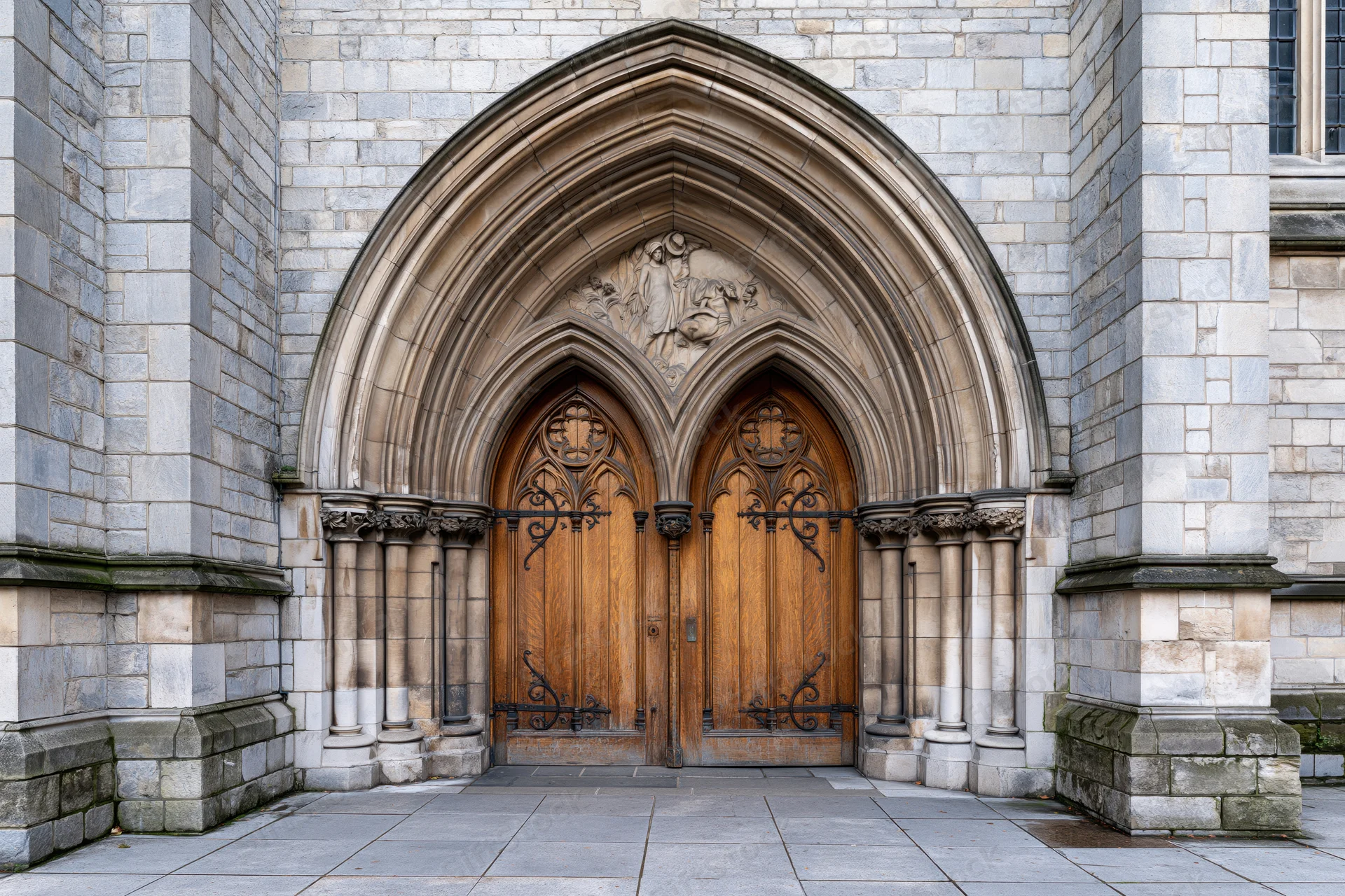 Gothic church entrance with ornate carved wooden double doors under stone archway