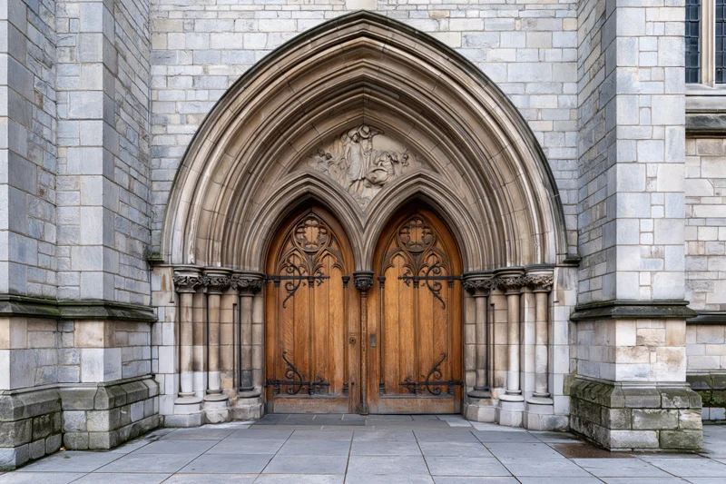 Gothic church entrance with ornate carved wooden double doors under stone archway