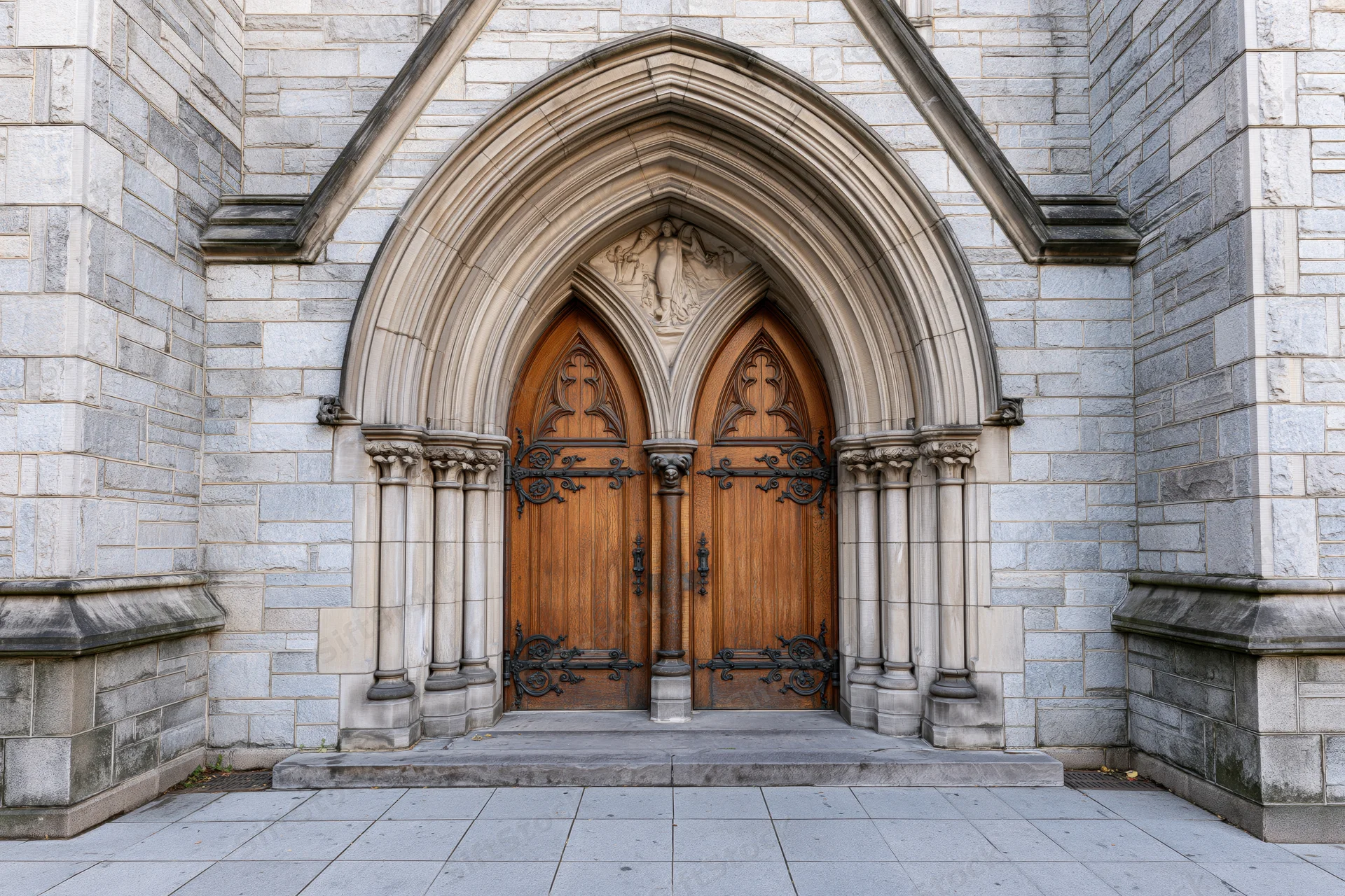 Gothic church entrance with ornate carved wooden double doors under stone archway