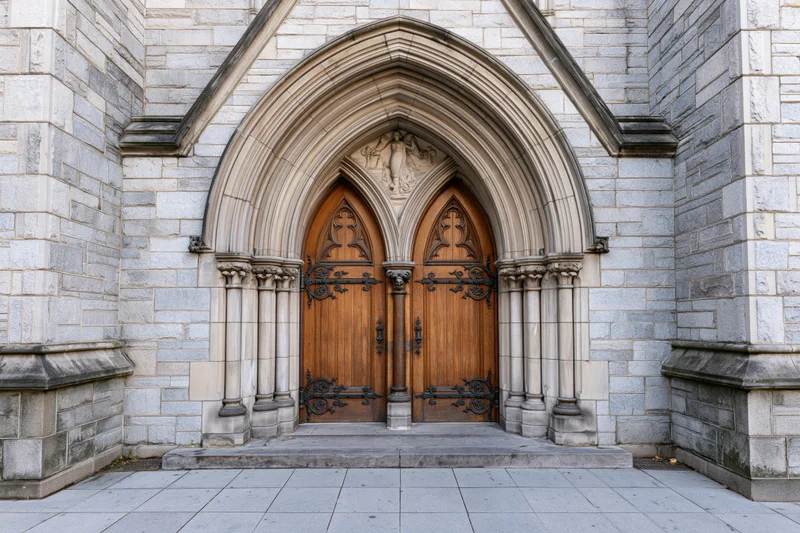 Gothic church entrance with ornate carved wooden double doors under stone archway