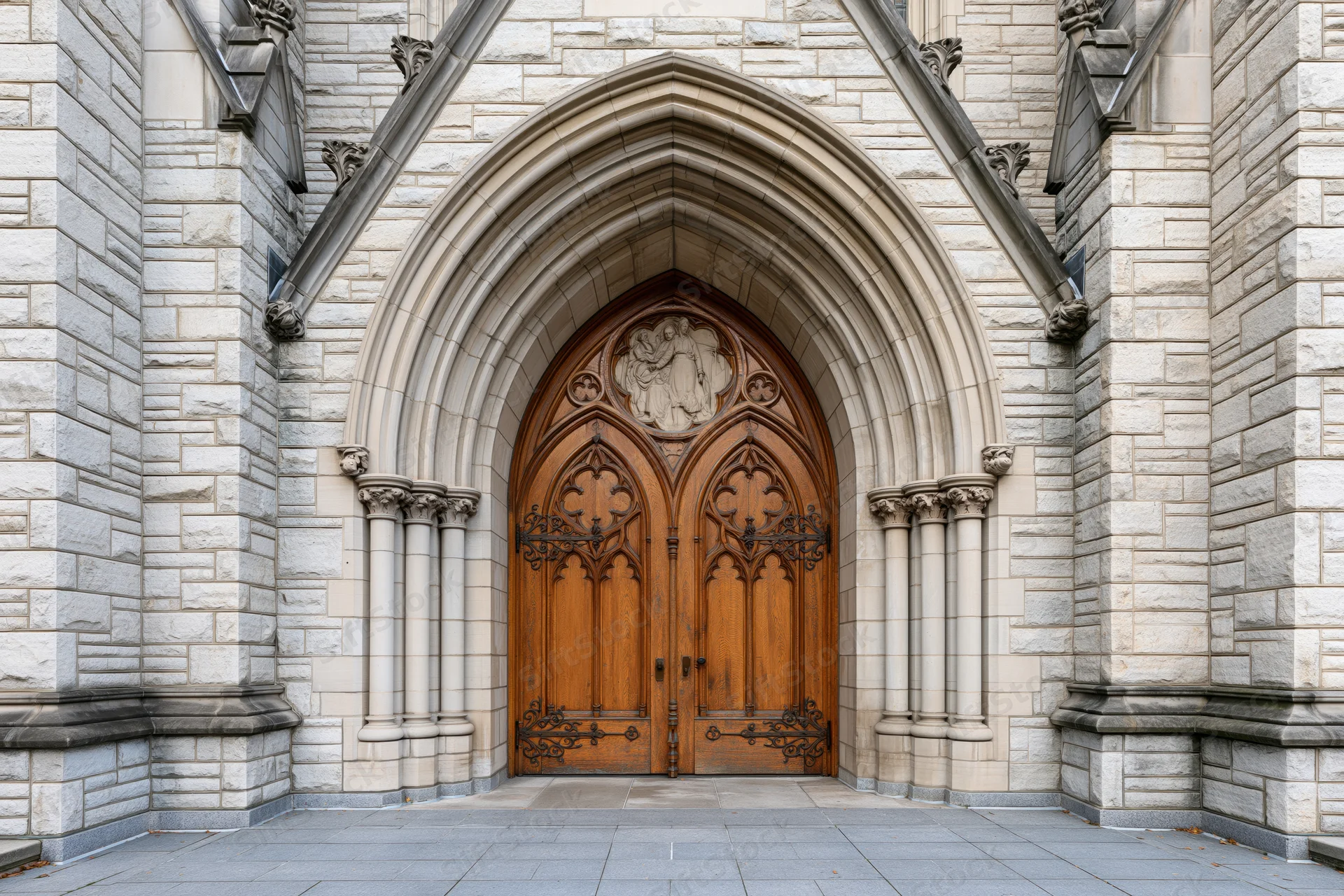 Gothic church entrance with ornate carved wooden double doors under a pointed stone arch