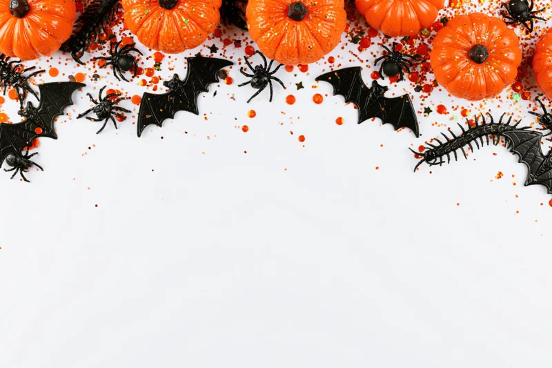 Halloween decorations arranged in a flat lay on white background with copyspace