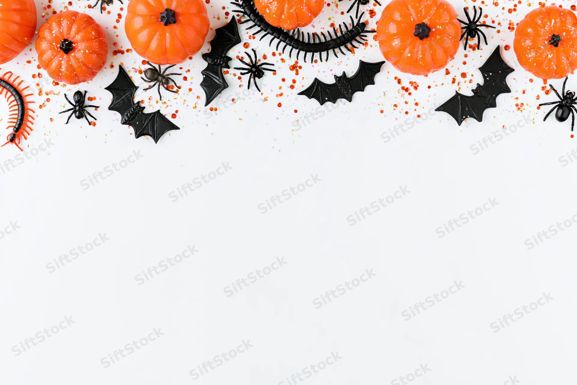 Halloween decorations arranged in a border along the top of a white surface with copyspace below
