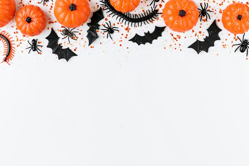 Halloween decorations arranged in a border along the top of a white surface with copyspace below