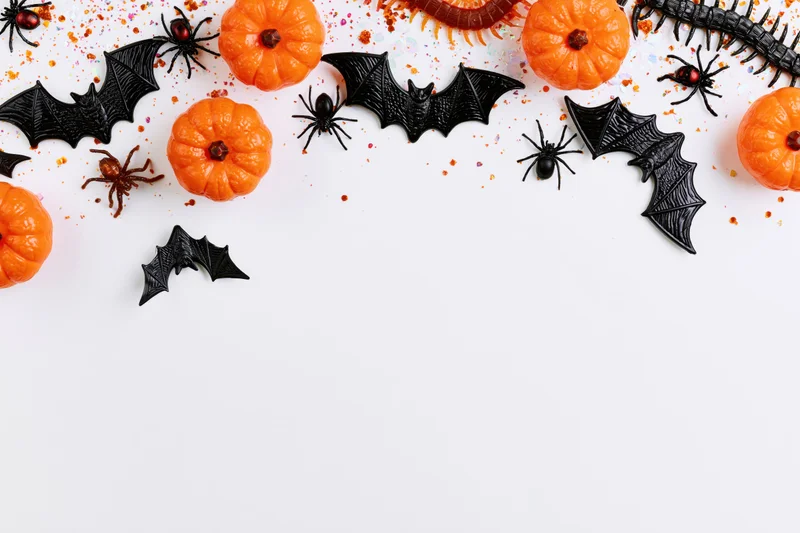 Halloween decorations arranged in a border along the top of a white surface with copyspace below