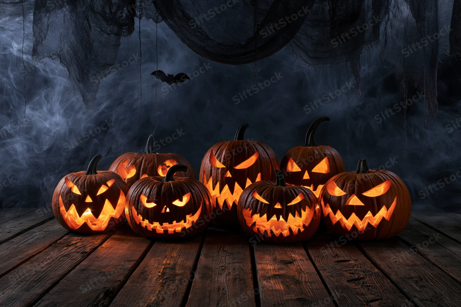 Carved jack-o-lanterns glowing on a wooden floor with smoke and cobwebs in the background