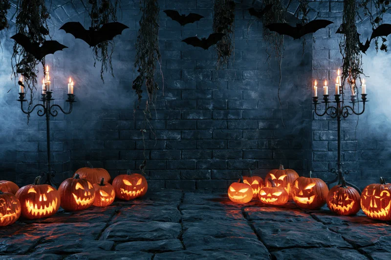 Carved jack-o-lanterns glowing on a stone floor against a brick wall with bats and candles in a spooky halloween scene