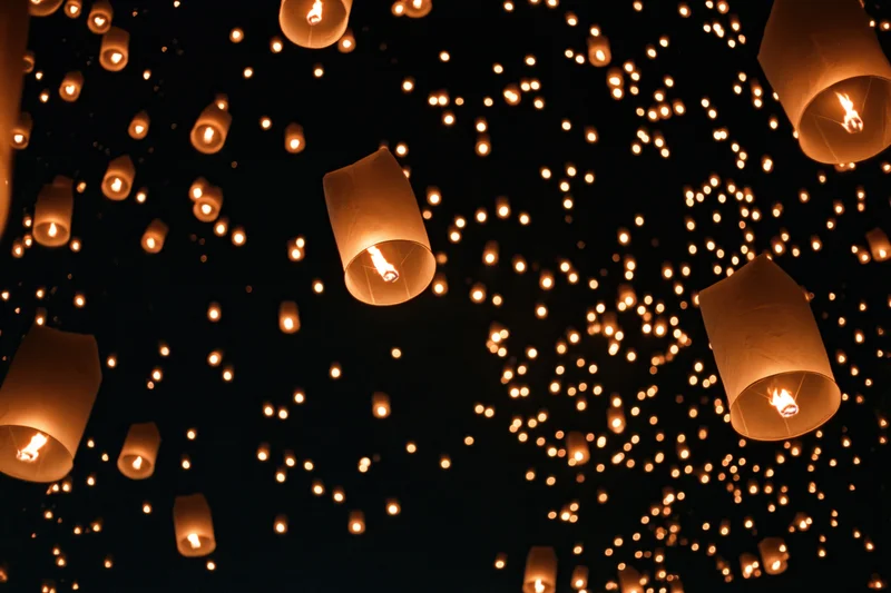 Paper sky lanterns floating upward into the night sky