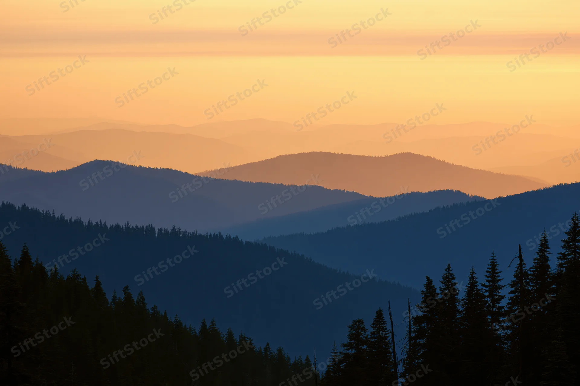Layered mountain ridges silhouetted against a hazy orange sky at sunset with dense pine forest in foreground