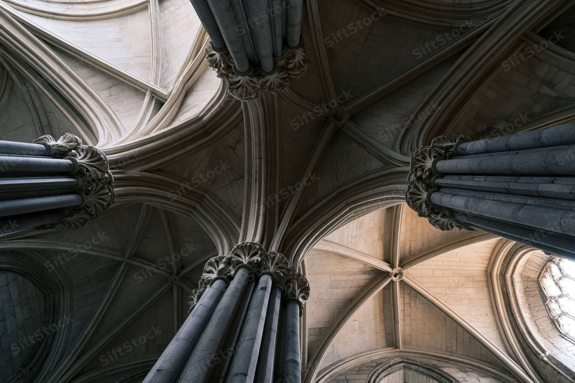 Upward view of gothic cathedral stone columns and ribbed vault ceiling