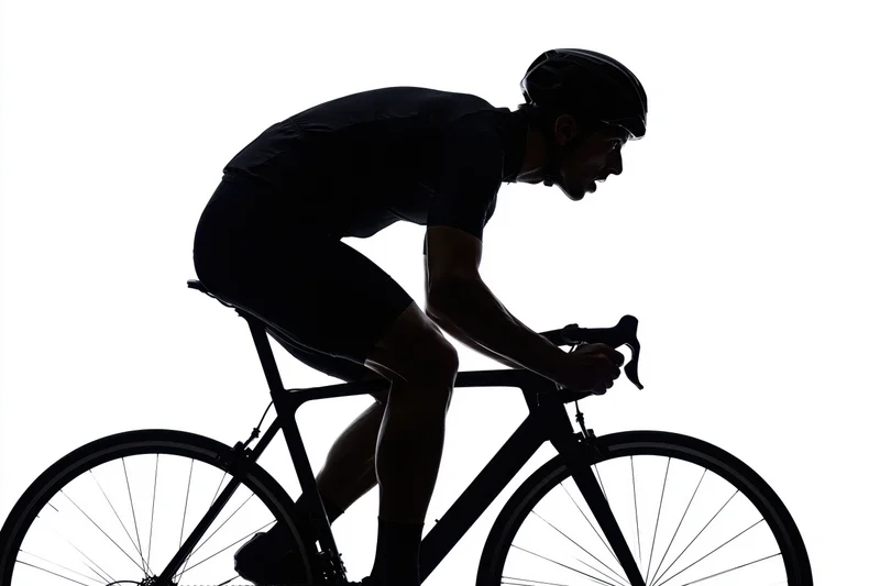 Male cyclist in aerodynamic posture riding a road bicycle against white background