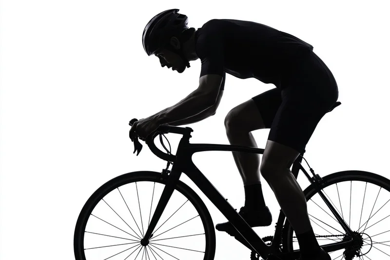 Male cyclist in aerodynamic forward-leaning posture on road bicycle silhouette