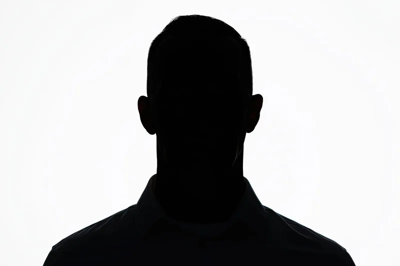 Silhouette of a man facing forward in a collared shirt against white background
