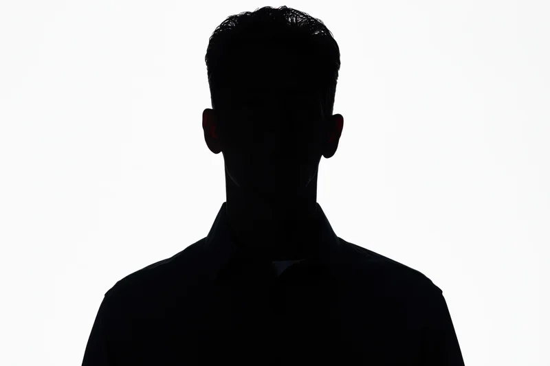 Silhouette of a man in a collared shirt facing forward against white background