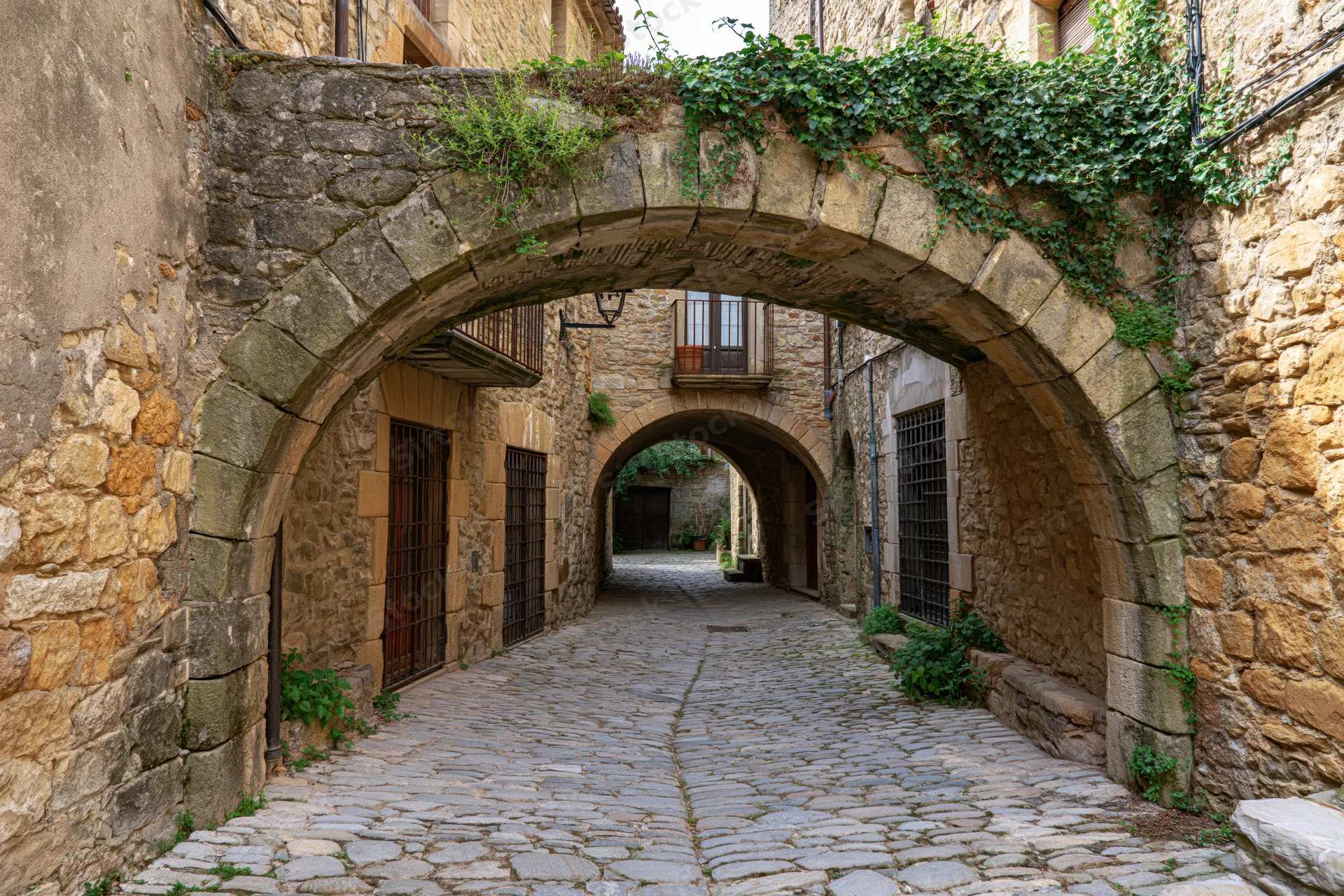 Narrow cobblestone alley under stone arches in a medieval Catalan village