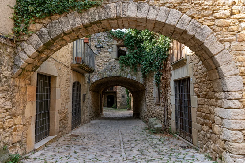 Narrow cobblestone alley under stone arches in a medieval Catalan village