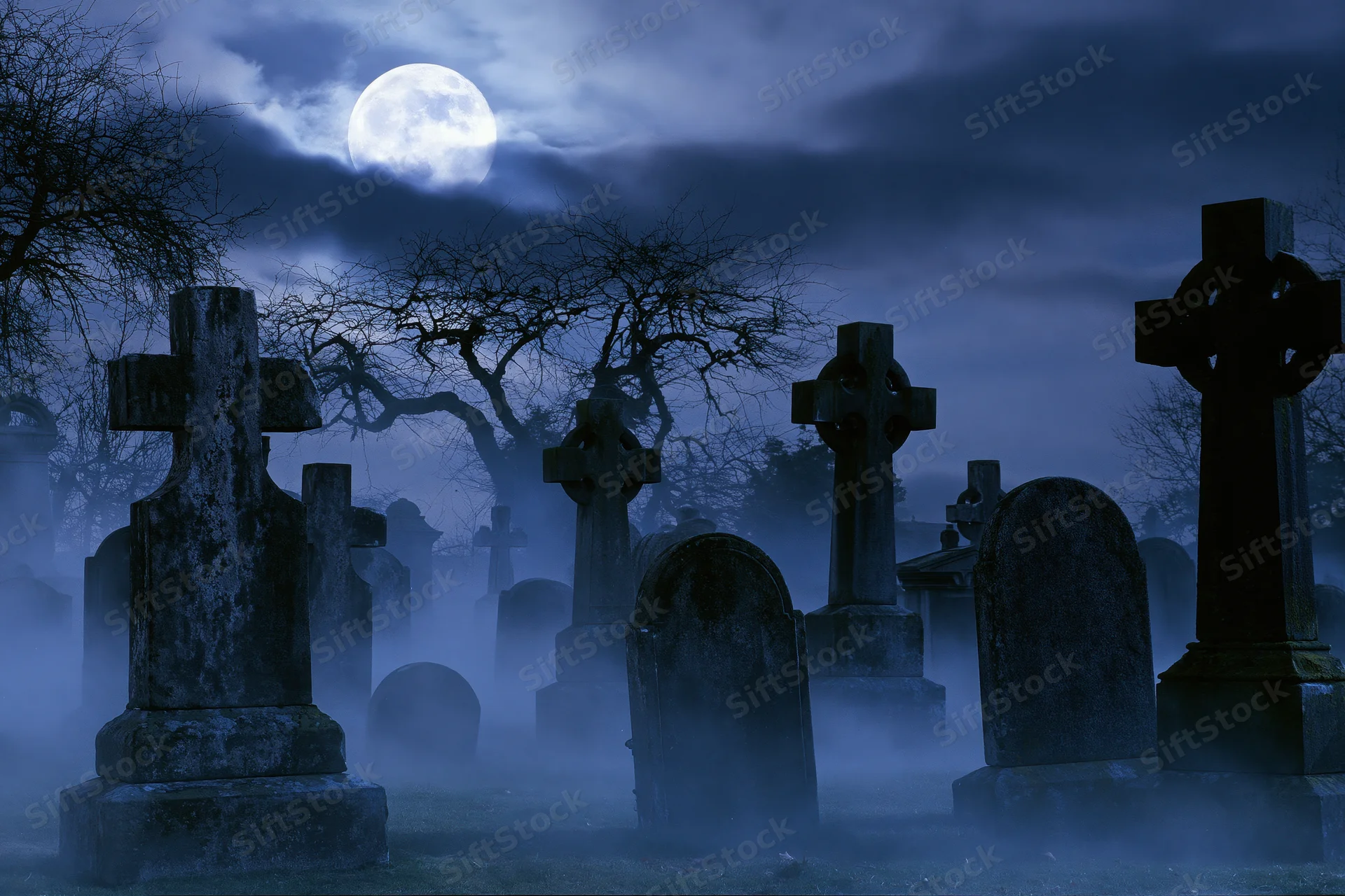 Old cemetery at night with weathered stone crosses and tombstones under a full moon in fog