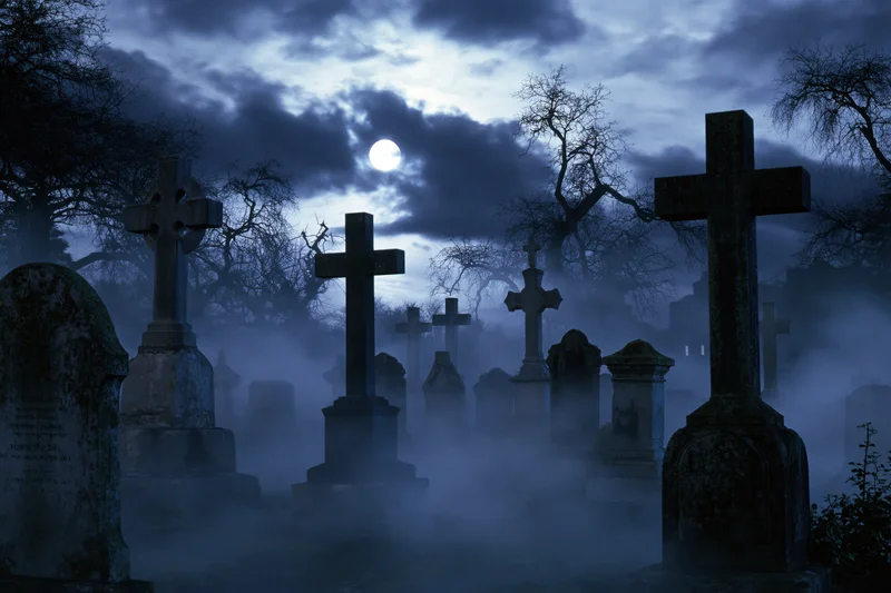 Foggy old cemetery at night with weathered stone crosses and tombstones under a full moon