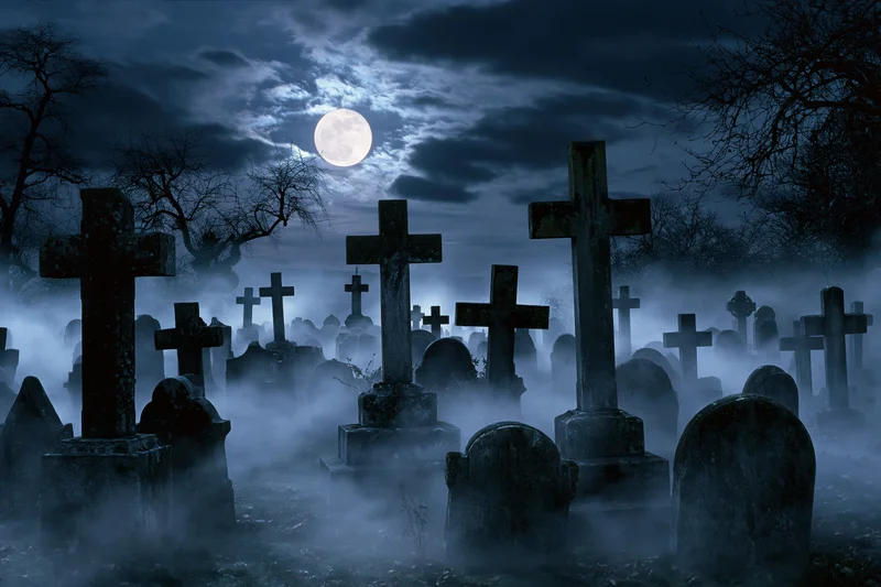 Old cemetery at night with weathered stone crosses and tombstones in fog under full moon