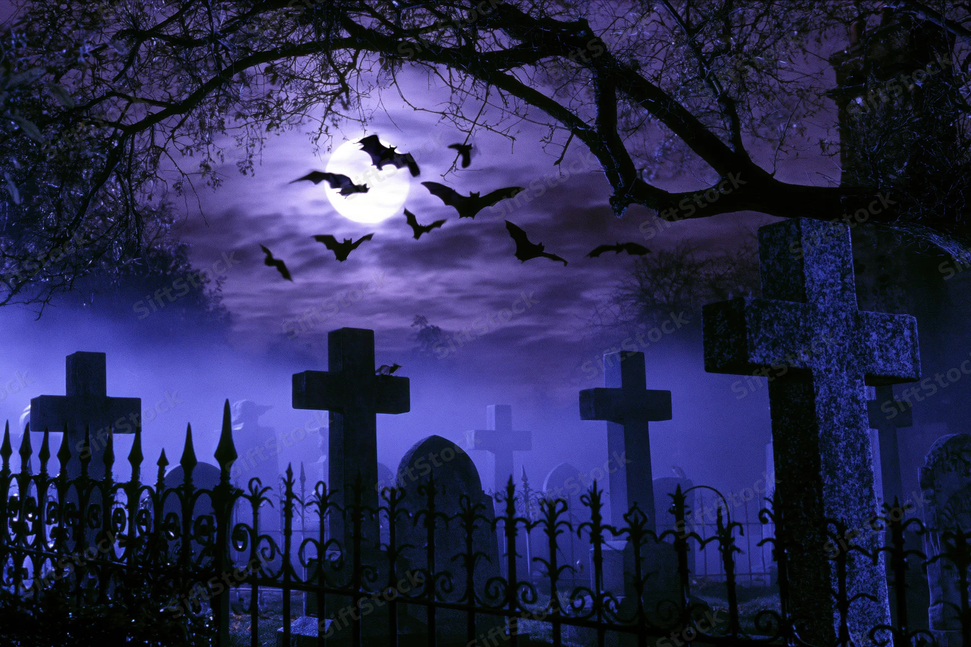 Old graveyard at night with stone crosses and wrought iron fence under full moon and flying bats