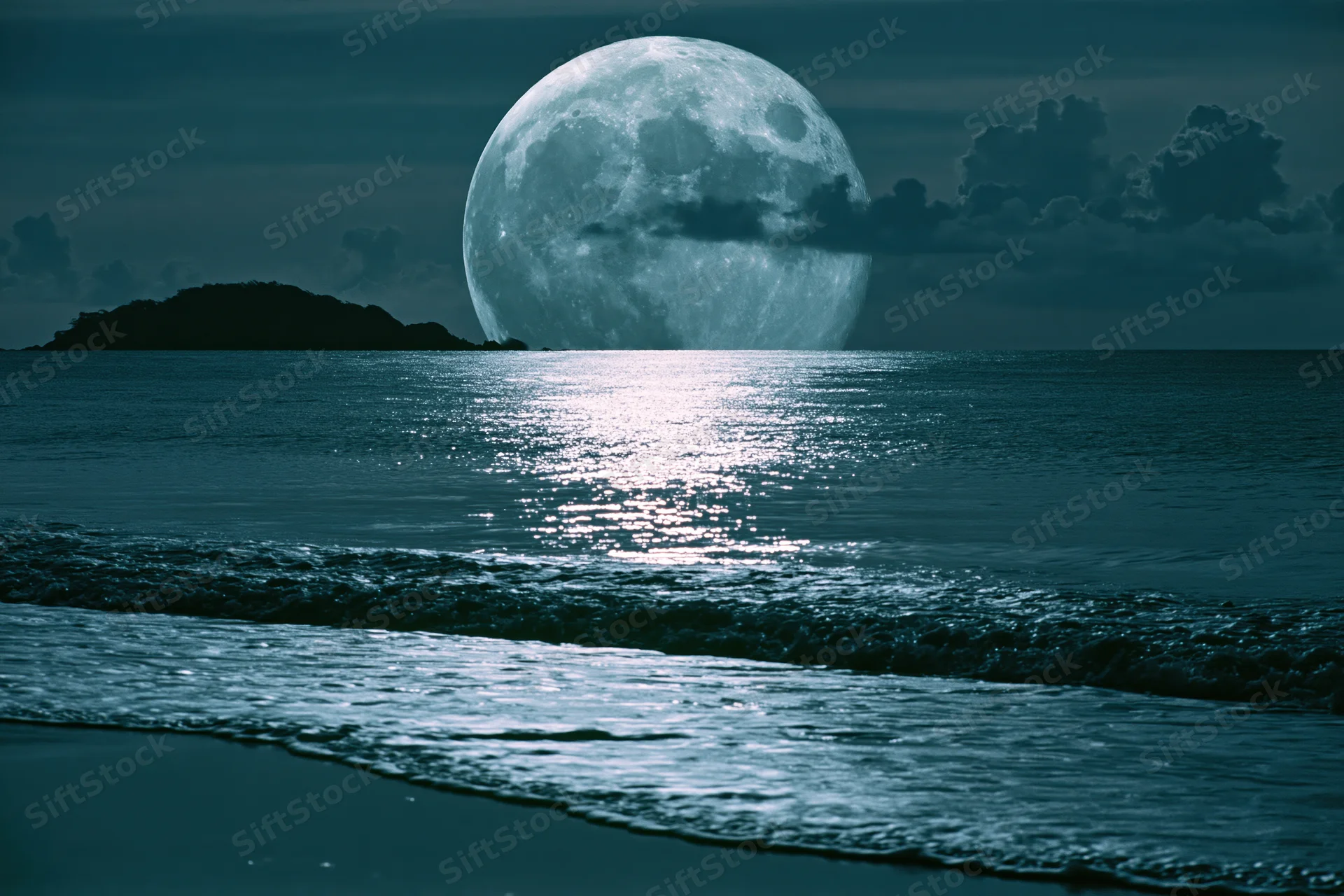Full moon rising over calm ocean at night with reflection on water surface near shore