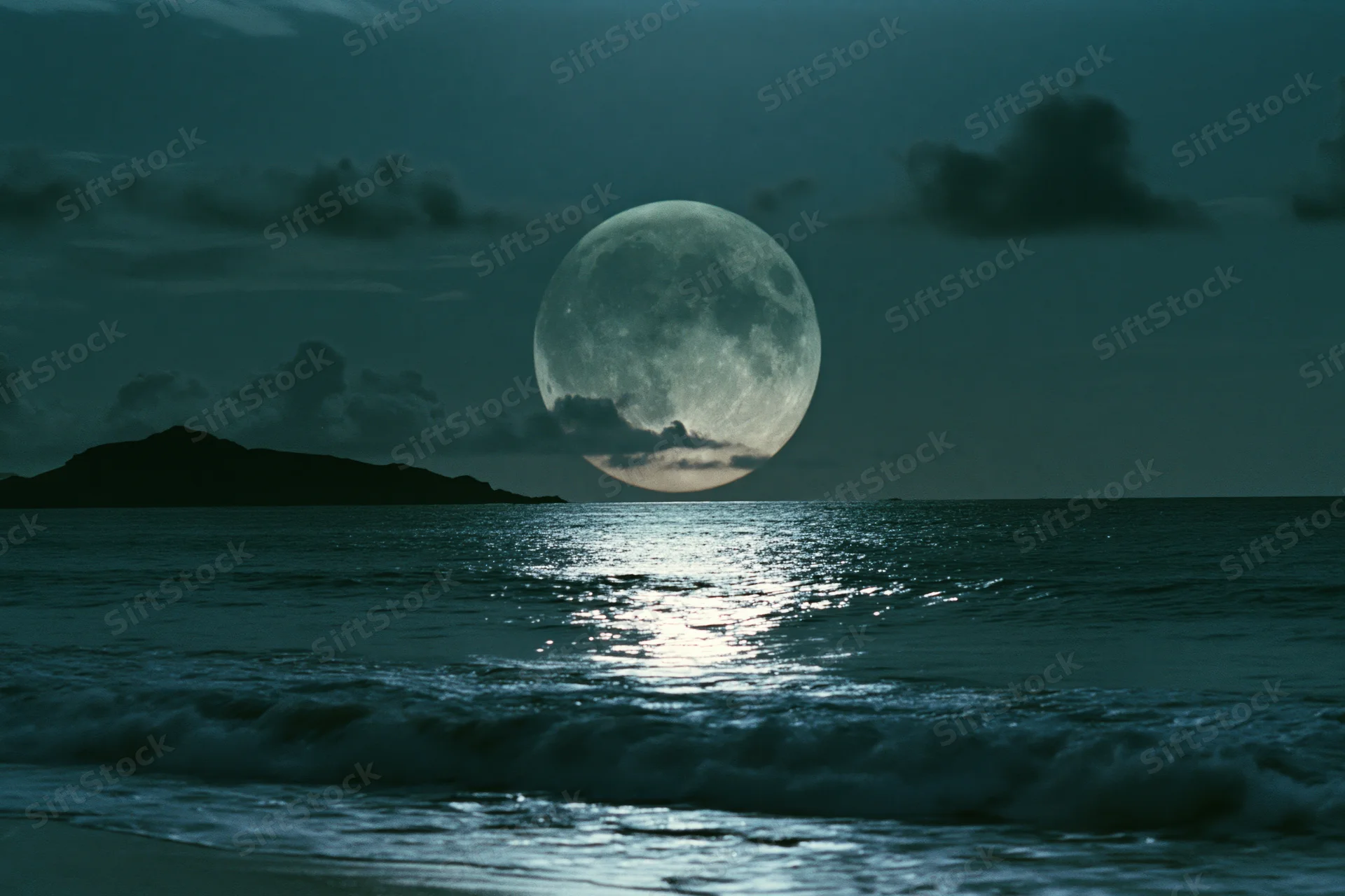 Full moon rising over calm ocean at night with reflection on water and distant island silhouette