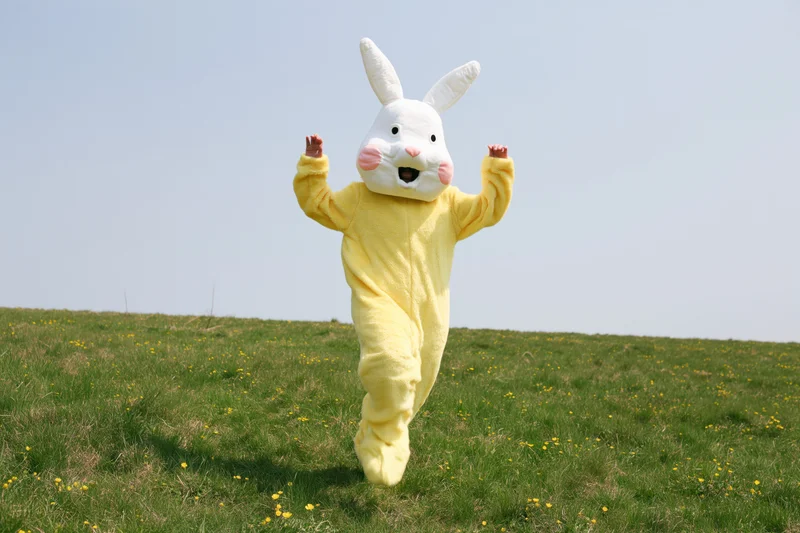 Person in yellow easter bunny costume running across grassy field