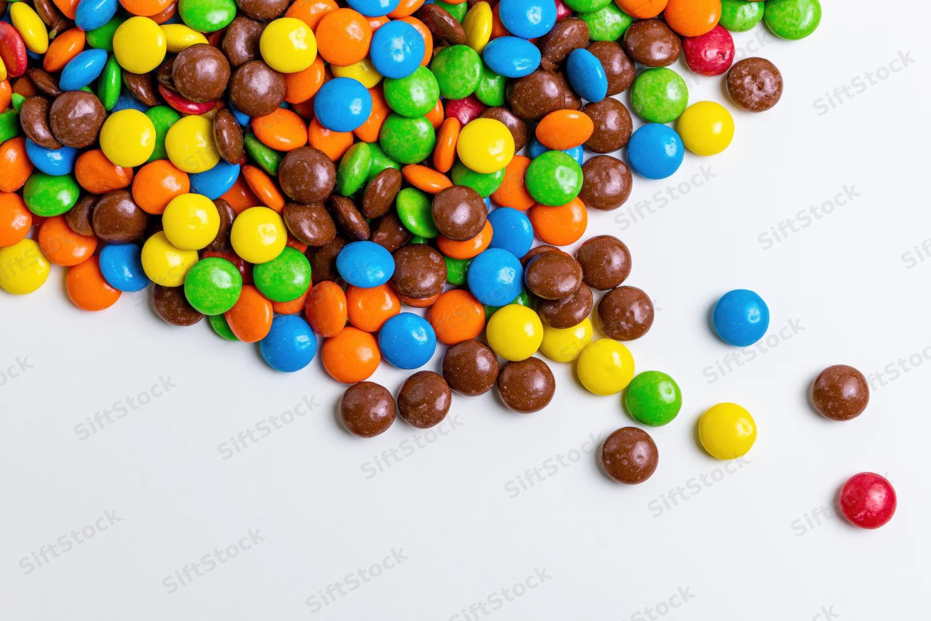 Colorful button candies scattered in a pile on a white background