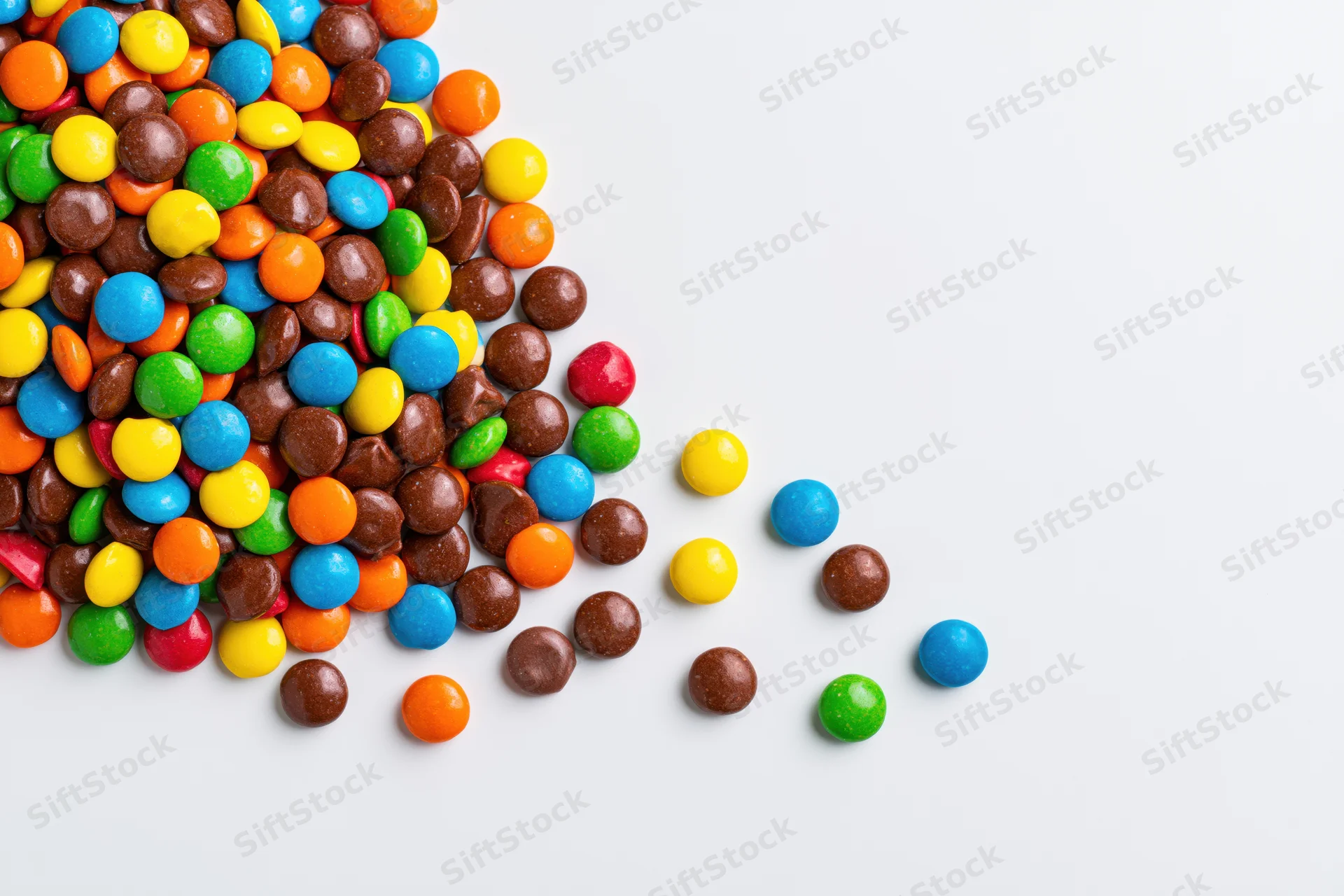 Pile of colorful button candies scattered across white background with copyspace