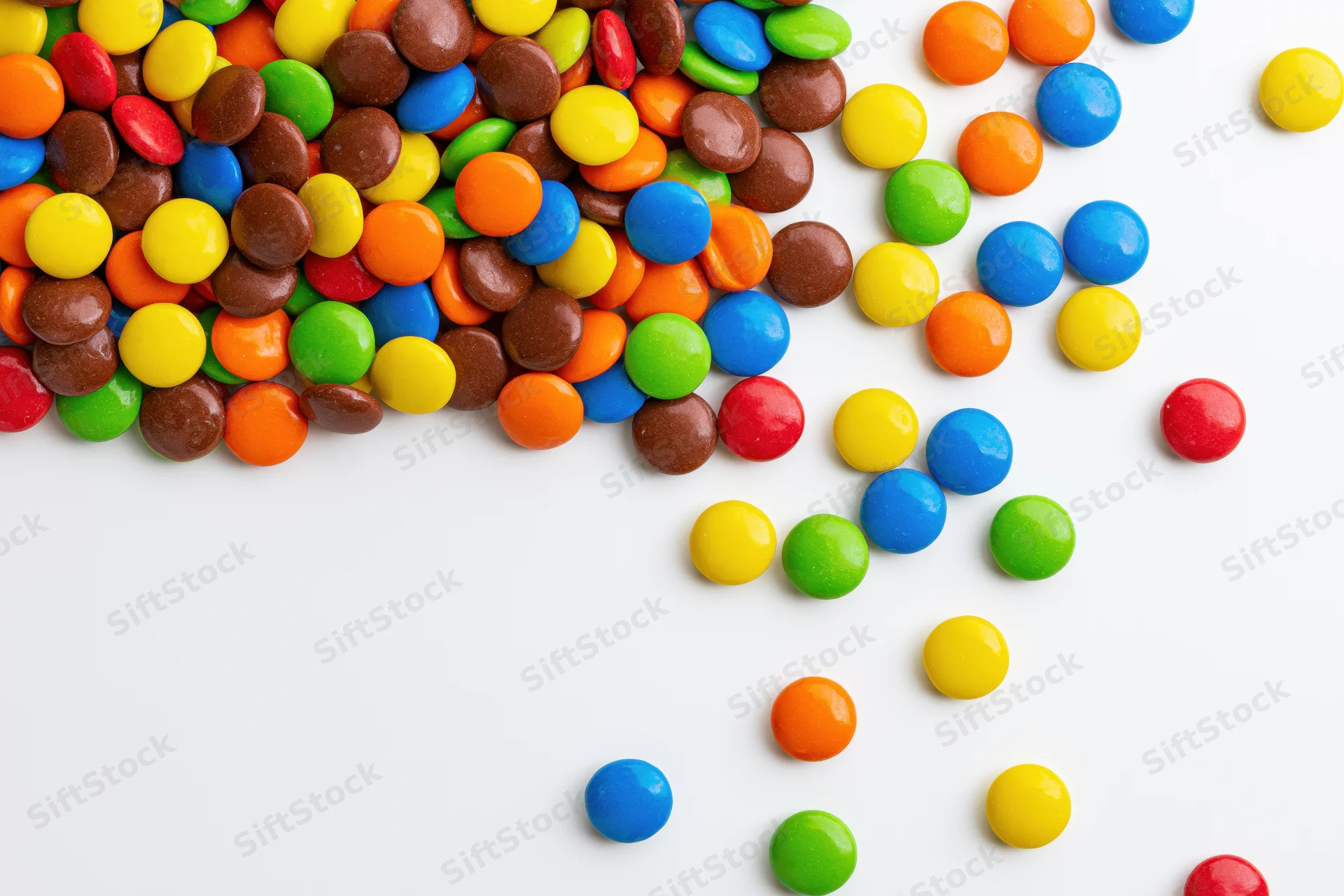 Colorful button candies scattered across white background with copyspace