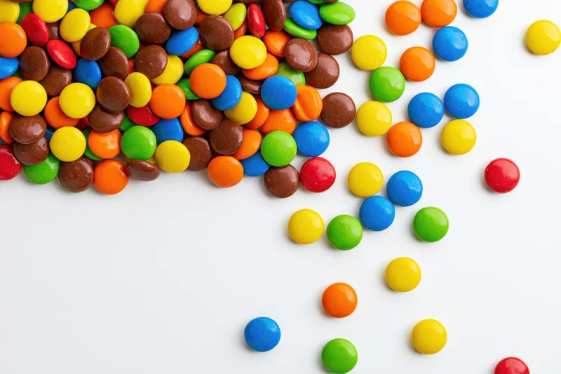 Colorful button candies scattered across white background with copyspace