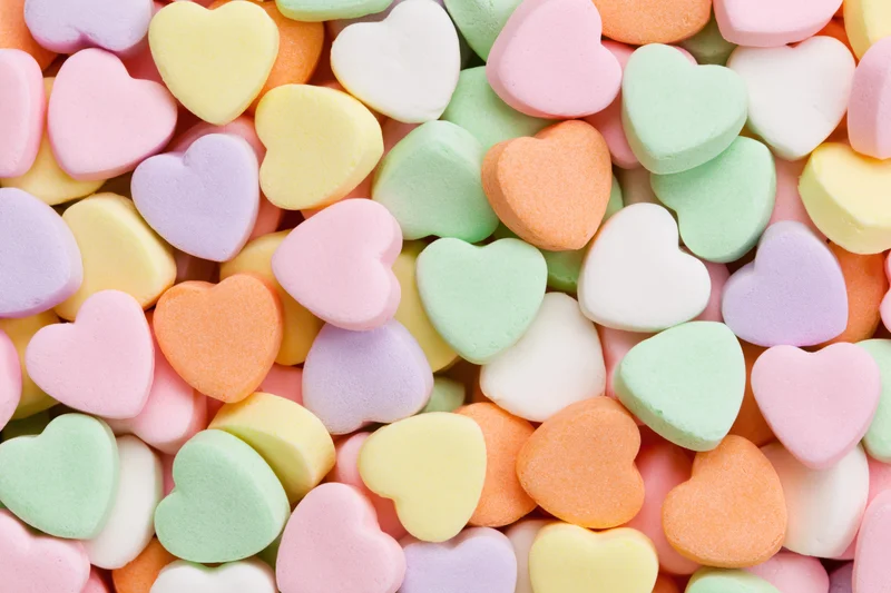 Pastel heart-shaped candies piled together in a flat lay view