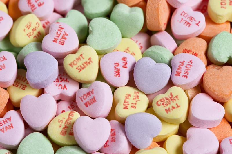 Pile of pastel heart-shaped candies with love messages scattered together