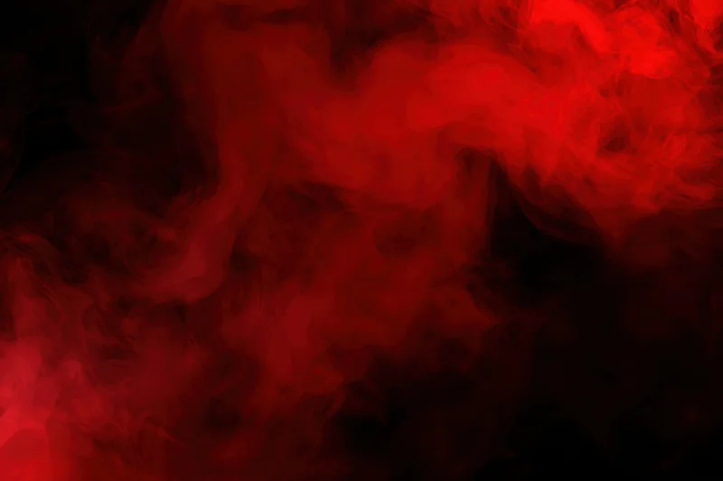Swirling red smoke drifting in dark clouds against black background