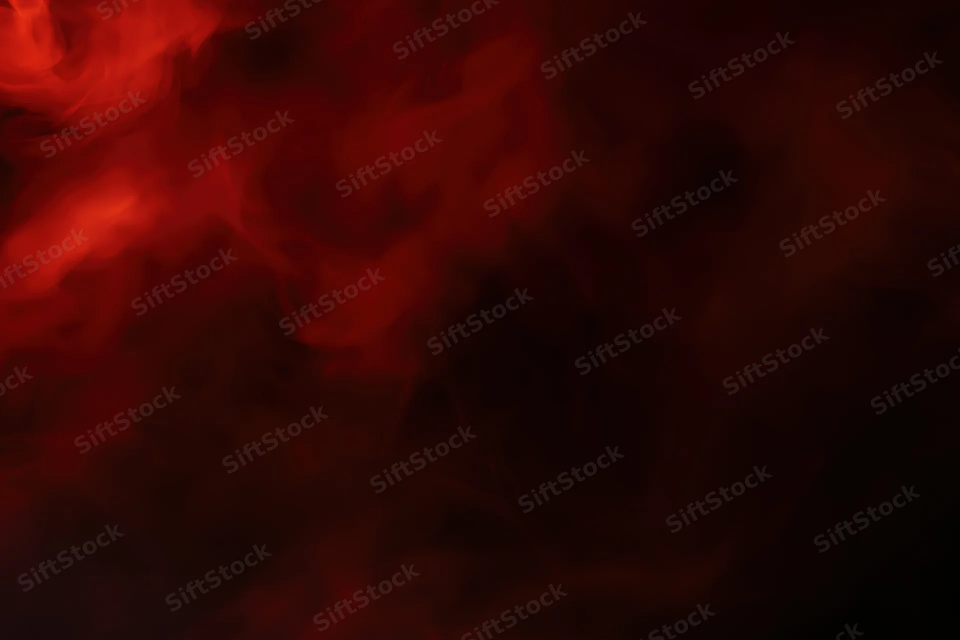 Swirling red smoke drifting in dark abstract clouds