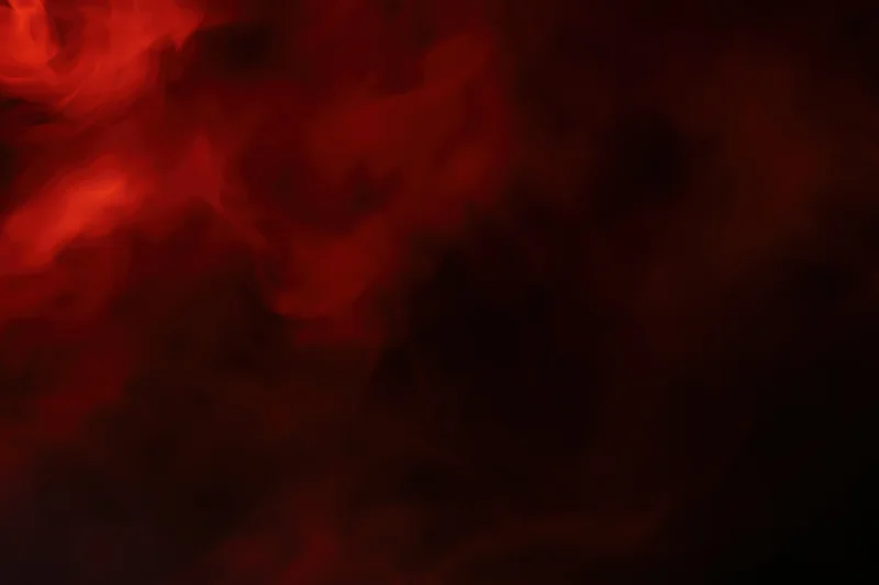 Swirling red smoke drifting in dark abstract clouds