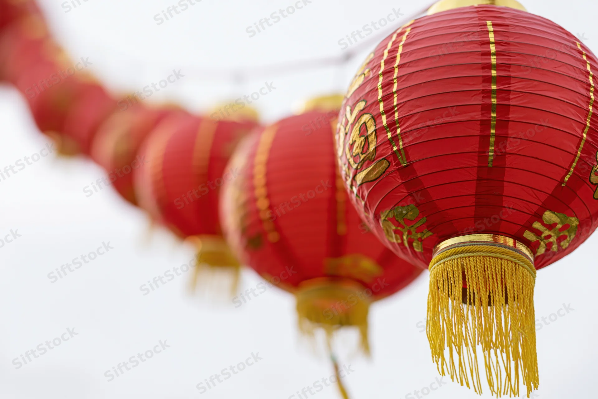 Row of red chinese paper lanterns hanging on a string outdoors
