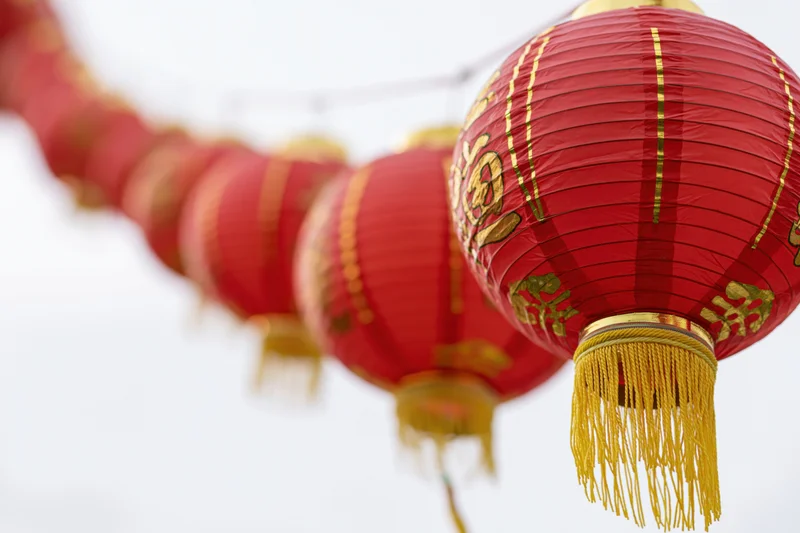 Row of red chinese paper lanterns hanging on a string outdoors