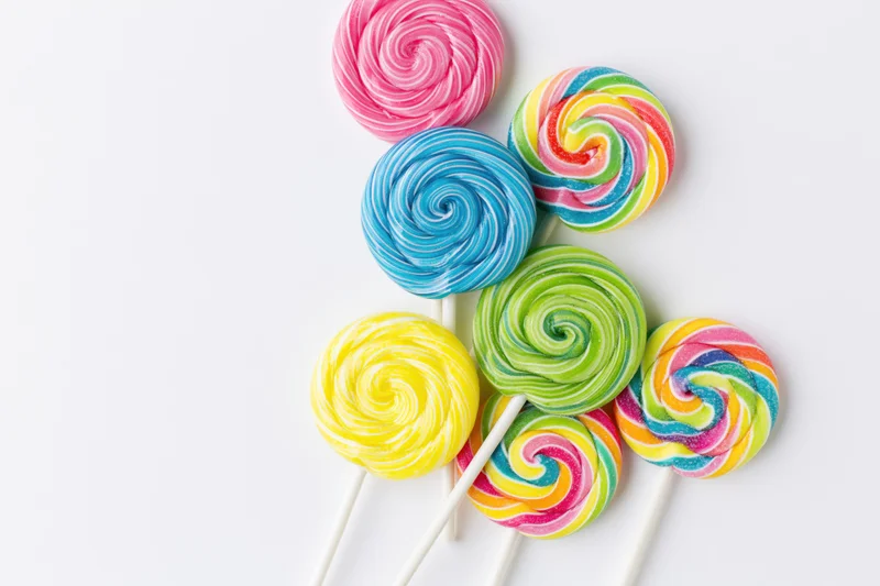 Colorful swirl lollipops arranged on white surface with copyspace