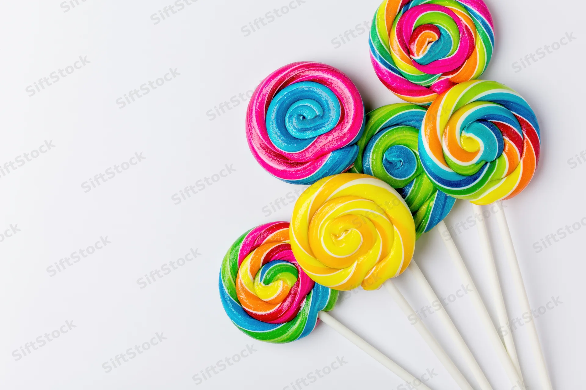 Colorful swirl lollipops arranged on white background with copyspace