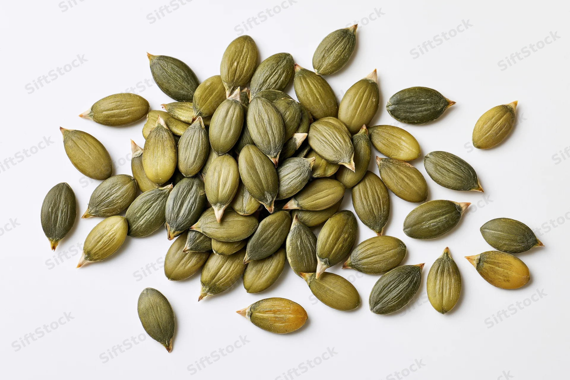 Shelled pumpkin seeds scattered on a white surface
