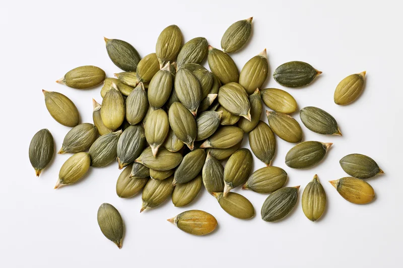 Shelled pumpkin seeds scattered on a white surface
